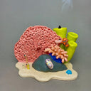Ceramic sculpture of an under sea theme, with pink and green coral, a sea anemone, stones, fish and various other sea creatures.