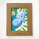 Framed artwork of a blue koala surrounded by green leaves on a white background