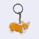 Die cut keychain of an illustrated brown corgi dog, smiling with its tongue out.l