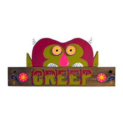 Die cut painted wooden sculpture of a horizontal board that reads "Creep" in stylized letters. Coming out the top is a furry monster, green and fuchsia with small horns, round eyes and a large pink nose. 