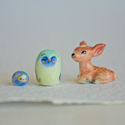 3 character sculptures - a sitting deer, a green owl, and a small circular character with a white face and blue body.