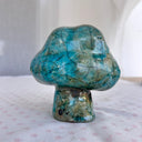 Raku fired ceramic sculpture of a piece of broccoli, with a cloud shaped top, a set of black eyes and a tiny stem for a body. 