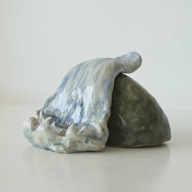 Ceramic sculpture of a waterfall over a rock.