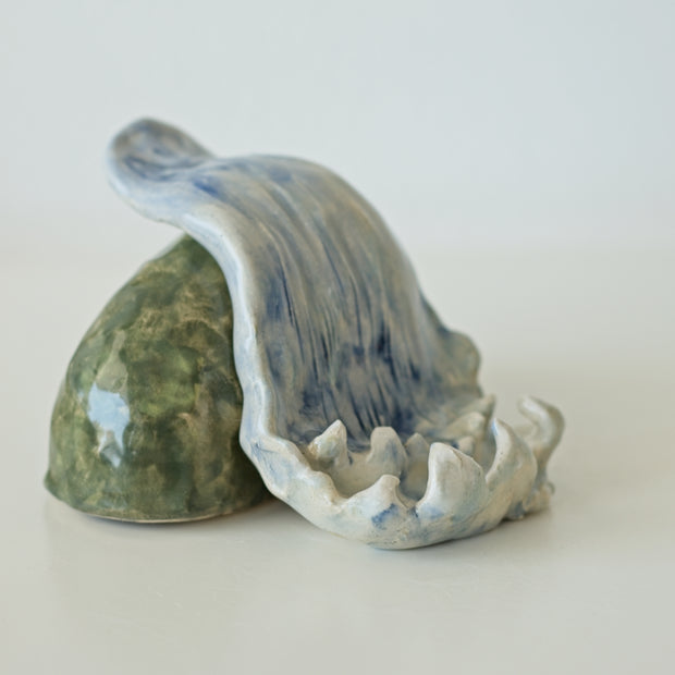 Ceramic sculpture of a waterfall over a rock.