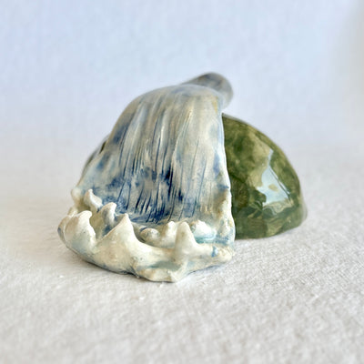 Ceramic sculpture of a waterfall over a rock.