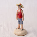 Ceramic sculpture of Luffy from One Piece, standing on a mound that looks like sand, with his iconic straw hat and his arms at his side.