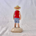 Ceramic sculpture of Luffy from One Piece, standing on a mound that looks like sand, with his iconic straw hat and his arms at his side.