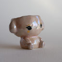 Shiny ceramic sculpture of a sitting cartoon bunny, with its head open and functional as a cup.