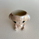 Shiny ceramic sculpture of a sitting cartoon bunny, with its head open and functional as a cup.