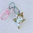 Small ceramic figure of a unicorn with a gold horn and gold detailings, attached to a keychain.
