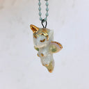 Small ceramic figure of a unicorn with a gold horn and gold detailings, attached to a keychain.