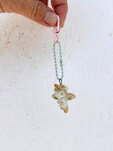 Small ceramic figure of a unicorn with a gold horn and gold detailings, attached to a keychain.
