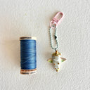 Small ceramic figure of a unicorn with a gold horn and gold detailings, attached to a keychain.