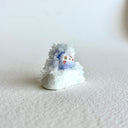 Small ceramic figurine of a circular character with small crystals all over it.