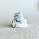 Small ceramic figurine of a circular character with small crystals all over it.