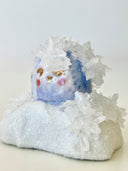 Small ceramic figurine of a circular character with small crystals all over it.