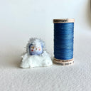Small ceramic figurine of a circular character with small crystals all over it.