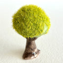 Ceramic tree with green grass flocking on the exterior of the tree top.