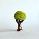 Ceramic tree with green grass flocking on the exterior of the tree top.