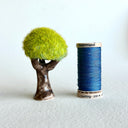 Ceramic tree with green grass flocking on the exterior of the tree top.