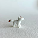 Small ceramic sculpture of a white fox with red and gold detail coloring.