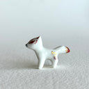 Small ceramic sculpture of a white fox with red and gold detail coloring.