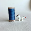 Small ceramic sculpture of a white fox with red and gold detail coloring.