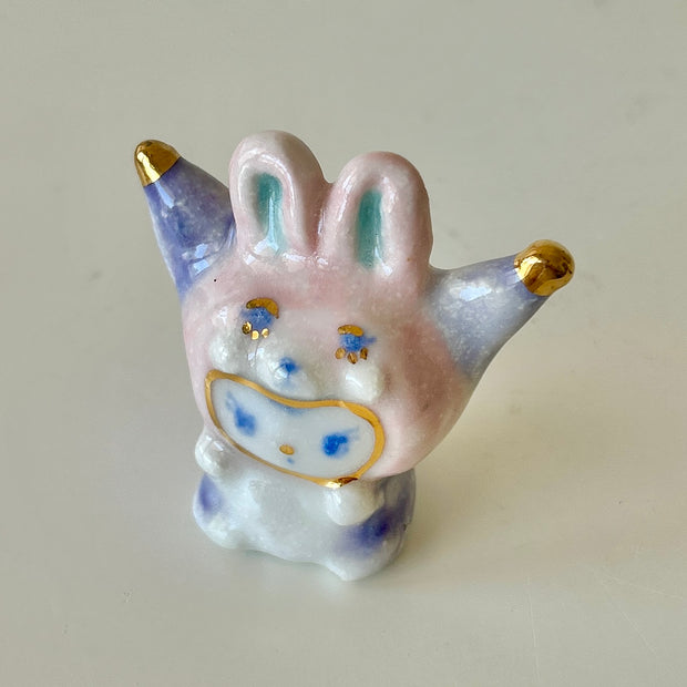 Ceramic rabbit figurine with gold and blue accents on a plain background