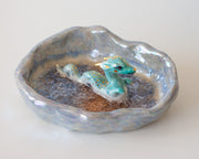 Ceramic dish with a blue dragon figurine on a white background