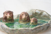 Ceramic dish made to look like a circular onsen in the snow with 3 monkeys bathing in it.