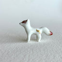 Small ceramic sculpture of a white fox with red and gold detail coloring.