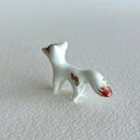 Small ceramic sculpture of a white fox with red and gold detail coloring.