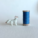 Small ceramic sculpture of a white fox with red and gold detail coloring.