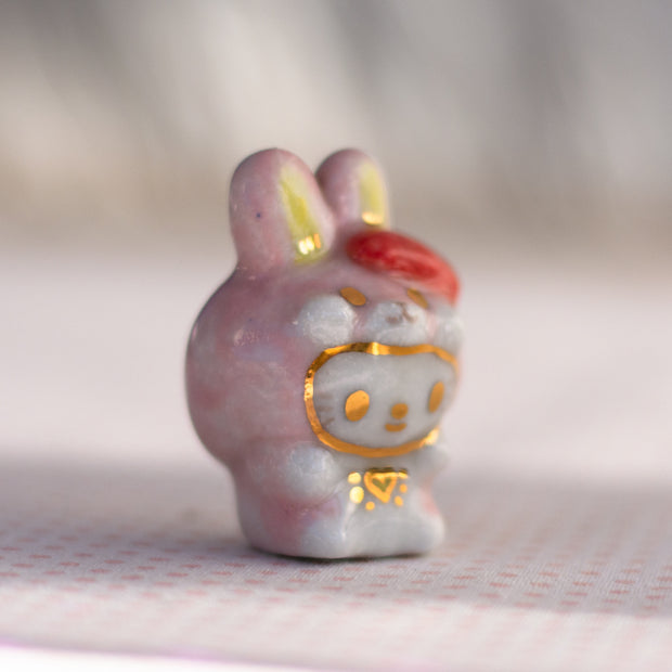 Ceramic rabbit figurine with a red bow on a textured surface