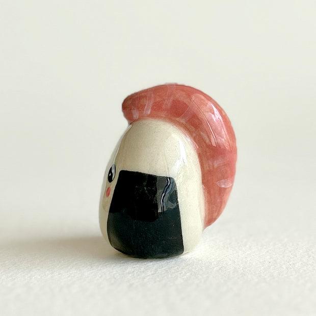Ceramic sculpture shaped like a piece of sushi or onigiri with a smiling face on a white background