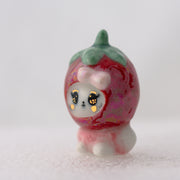 Ceramic strawberry figurine with a small animal face on a white background