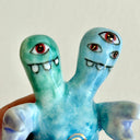 Small collection of sculptures: a house, a tiny red bridge, mountains and a 2-headed blue water monster.