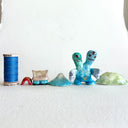 Small collection of sculptures: a house, a tiny red bridge, mountains and a 2-headed blue water monster.