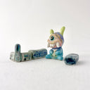 Small collection of sculptures: several buildings and a cyclops character with large rounded teeth.