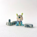 Small collection of sculptures: several buildings and a cyclops character with large rounded teeth.