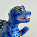 Small collection of sculptures: several buildings, a cherry blossom tree, green hill and a blue kaiju monster with gold dots.