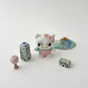 Small collection of sculptures: several buildings, a cherry blossom tree, blue mountain and a kitty monster with gold details.