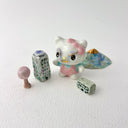 Small collection of sculptures: several buildings, a cherry blossom tree, blue mountain and a kitty monster with gold details.