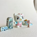 Small collection of sculptures: several buildings, a cherry blossom tree, blue mountain and a kitty monster with gold details.