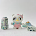 Small collection of sculptures: several buildings, a cherry blossom tree, blue mountain and a kitty monster with gold details.