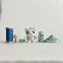 Small collection of sculptures: several buildings, a cherry blossom tree, blue mountain and a kitty monster with gold details.