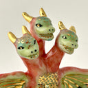 Small collection of sculptures: a three-headed monster, a small cherry blossom tree, green mountain and other nature elements.