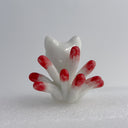 White ceramic cat figurine, sitting with 9 tails that are red-tipped. The cat's face and body has gold painted detailings.