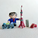 Small collection of sculptures: a business man with glasses, the Tokyo tower, small buildings and a red bridge.