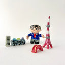 Small collection of sculptures: a business man with glasses, the Tokyo tower, small buildings and a red bridge.